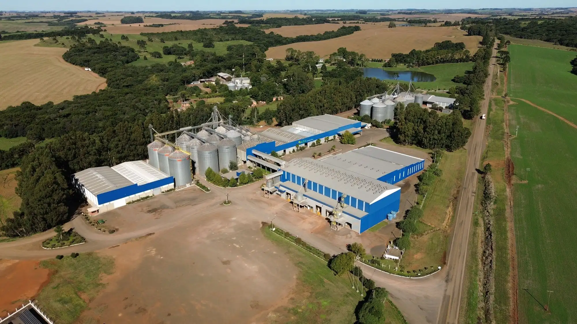Vista aérea da unidade da NBN Sementes em Vacaria: silos, galpões e usina solar cercados de lavoura.